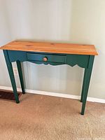 Front view of green base solid wood console table with natural top and drawer