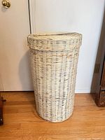 Front view of tall cream painted wicker hamper with lid