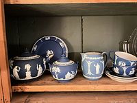 Full set on shelf showing teapot, sugar bowl, plate, creamer, teacups, saucers