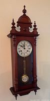 Full view of mahogany regulator wall clock hanging on wall