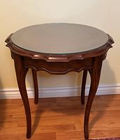 Full view of French Provincial round end table showing glass top, wood frame, cabriole legs