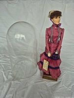 Doll beside detached glass dome on white backdrop