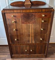 Front view of tall chest showing drawers, cabinet doors, crest top, overall condition