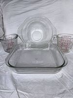Group shot of all four glass pieces: square dish front, mixing bowl rear, two measuring cups at sides