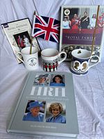 Group shot of all seven items: two books, one DVD, three mugs, Union Jack flag