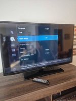 Front view of Samsung 40-inch TV on stand displaying menu with remote in foreground
