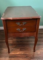 Front view of nightstand showing two ornate pulls and cabriole legs