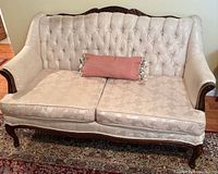 Front view showing overall settee, upholstery, cushions, carved frame