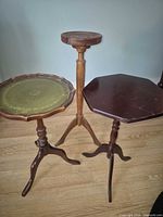 All three pedestal tables side by side showing height differences and finishes