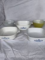 Group shot of all five pieces: three Cornflower casseroles, yellow bowl, grey bowl