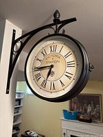 Clock mounted on wall bracket showing side profile, metal frame, cream dial