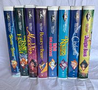Front spines of all eight Disney clamshell VHS tapes standing side-by-side