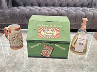 Front view of tin, stein and liquor bottle