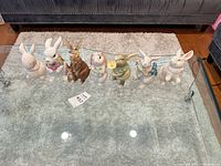All eight ceramic bunny figurines lined on glass table