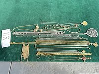 Overview of all necklaces laid out on green surface showing variety of chains and pendants