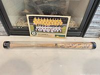 Overview of signed bat in plastic tube and 2013 team photo poster