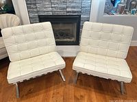 Pair of off-white Barcelona style chairs in front of fireplace