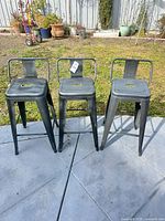 Three metal stools side by side outdoors