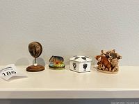 Four small trinkets lined on shelf