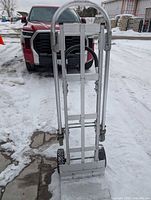 Full view of one aluminum convertible dolly standing upright on snowy ground