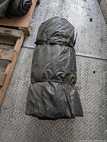 Full view of rolled black vinyl tarp secured with straps