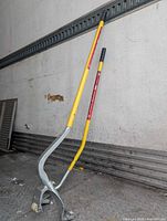 Full view of two long-handled tire tools leaning against wall