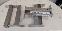 Four metal IKEA GRANHULT shelf brackets arranged on surface