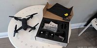 Drone and accessories laid out on table, controller in box