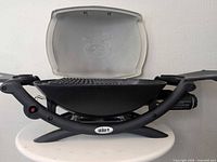 Overall view of Weber Q 1200 grill with lid open and side tables extended