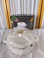 Dutch oven wrapped in plastic with box behind showing branding