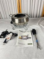 Full set laid out: pot on stand, control module with cord, six forks, booklet