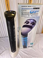 Front view of Sharper Image Ionic Breeze GP air purifier next to its retail box