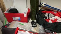 Group view of cooler, cot, chair sleeve, bags and headlamp