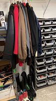Multiple coats and jackets on rack, footwear below