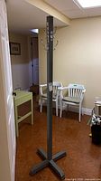 Full view of grey painted steel coat rack standing on cross base