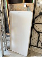 Front view of Lifetime plastic folding table leaning against wood table