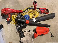 Group shot of Craftsman trimmer, Black & Decker blower, red hedge trimmer, yellow extension cord, blue trimmer line