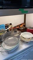 Overall view of casseroles, bowls, strainer, packaging on countertop