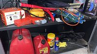 Shelf showing multiple automotive items including gas cans, WD-40, cords