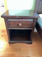 Front view of wood night stand showing drawer, knob, open shelf