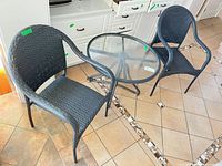 Two wicker-look chairs and round glass table overview