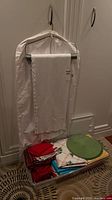Tablecloth on hanger above tote of assorted linens
