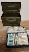 Overall view of open military box and open first aid kit showing contents