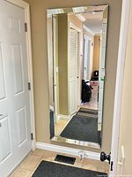 Full-length mirror mounted on wall showing frame design