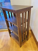 Three-shelf oak bookcase angled view showing vertical side slats and top