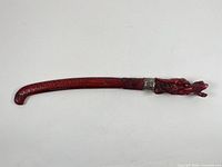 Full view of sword in sheath showing dragon head handle and curved sheath