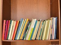 Shelf with approximately 40 soft-cover music scores angled upright