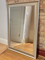 Front view of large rectangular silver framed mirror leaning against wall