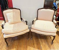 Full view of both carved walnut Louis XV style armchairs showing upholstery, cushions and frames