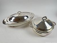 Both silver-plated dishes side by side showing size contrast and lids